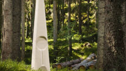 En konstinstallation i den värmländska skogen, omgiven av stora och höga granar.